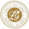 gold circular family crest with an ornate central monogram and the border text 'familia leza baeza' around the edge.